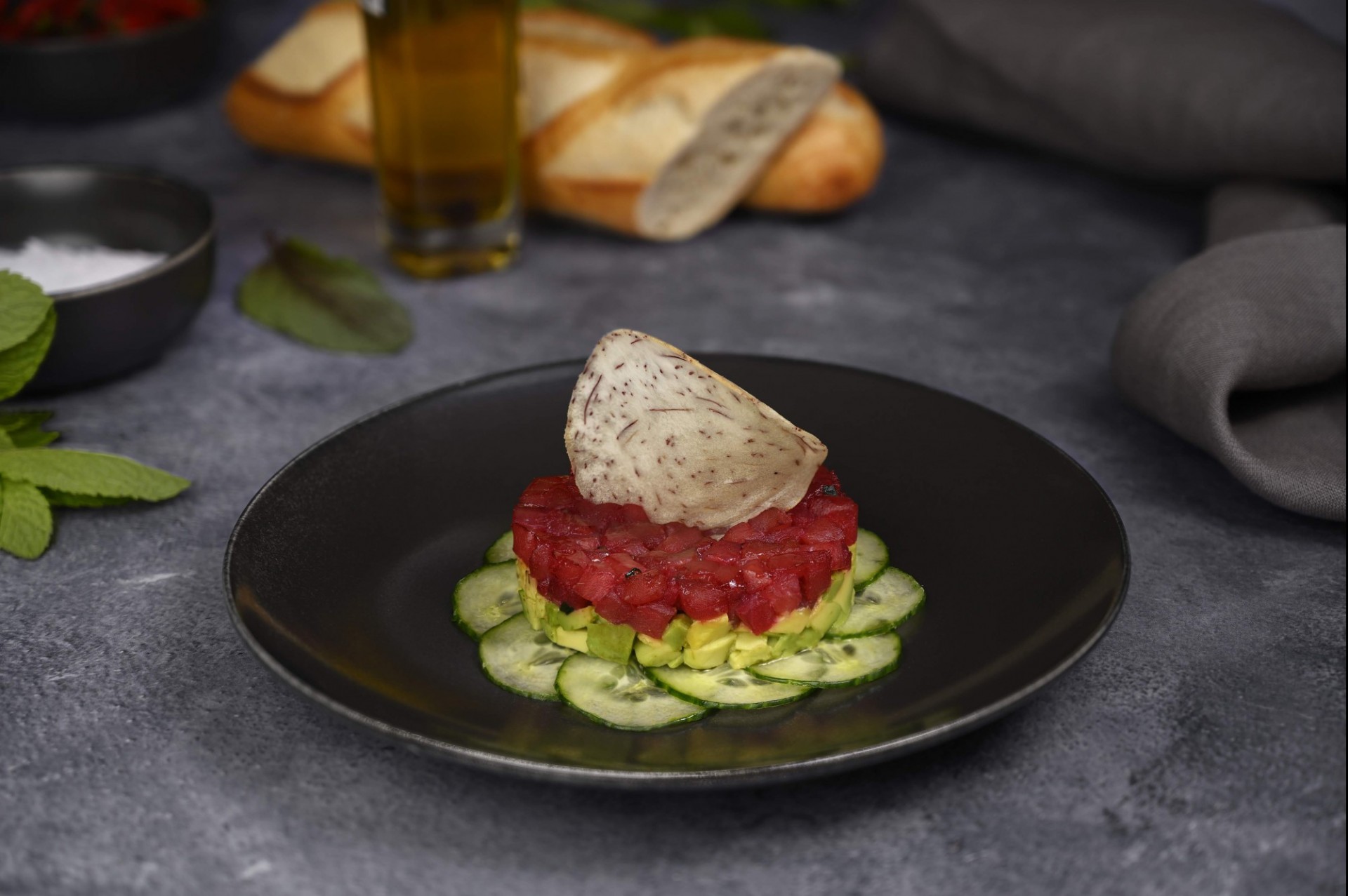 Tuna tartar topped with a taro chip sits on a bed of thinly sliced cucumber