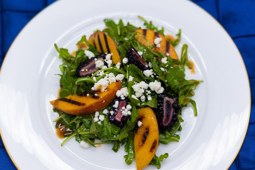 A salad with grilled peaches and arugula that is featured on the menu