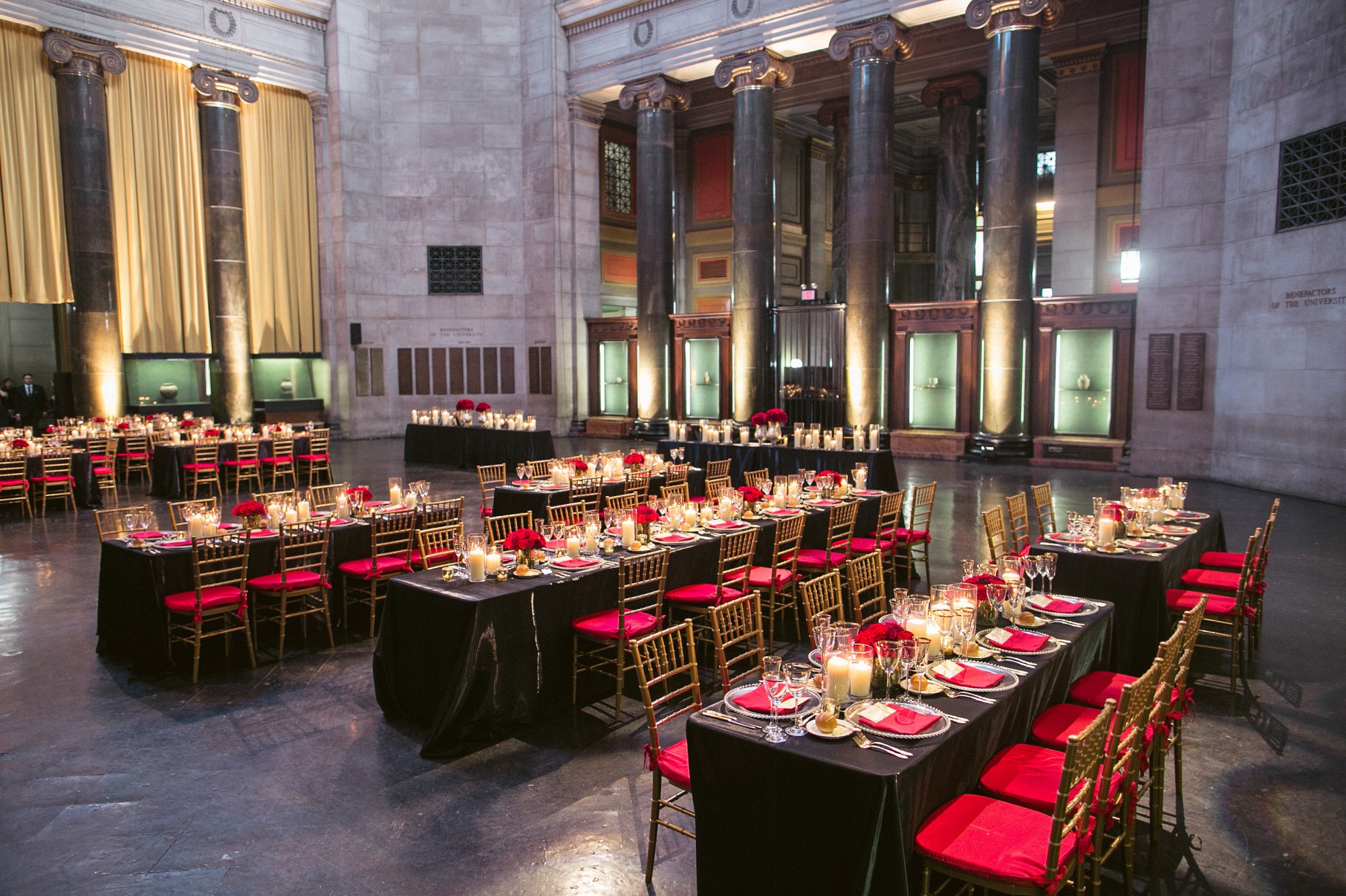 Rectangular tables dressed with black linens sit in a grand rotunda space. 