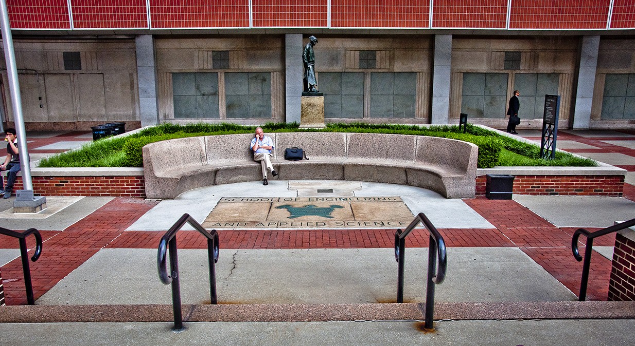 A man sitting on a granite bench at Mudd Terrace.