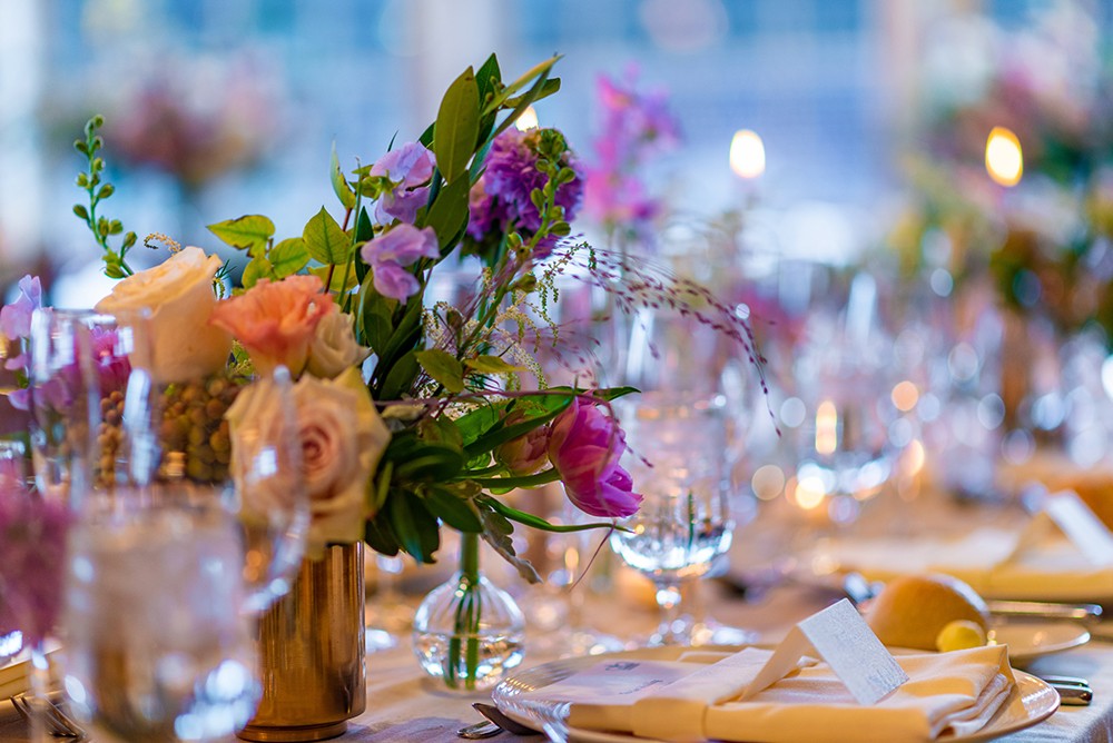 Beautiful flowers sitting on an elegantly decorated table with soft candlelight shining in the background.