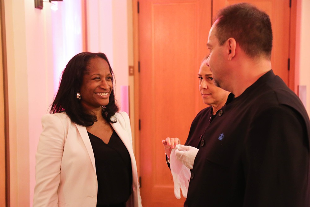 Several people at an event chat and smile at one another.