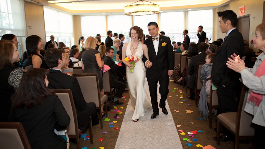 A bride and groom walk toward the camera down the aisle after saying their vows in a wedding ceremony at Faculty House