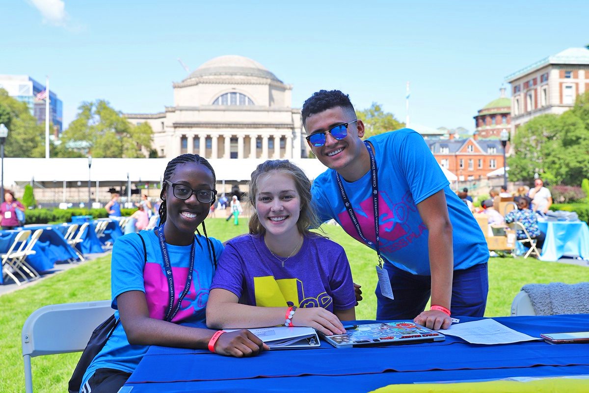 Three students sitting behind a table on Columbia University's south lawn.