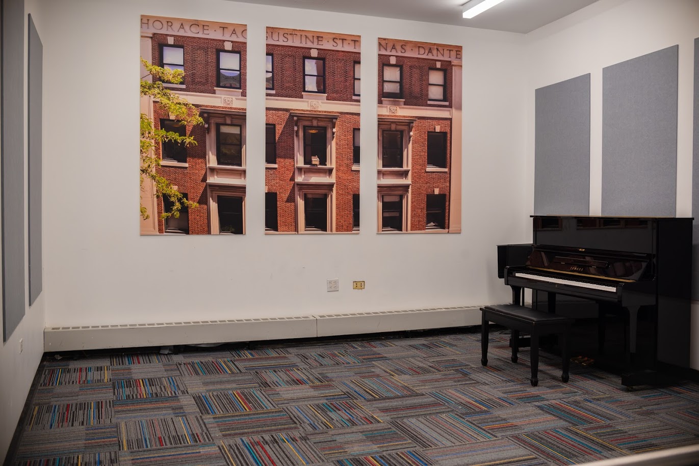 Grey acoustic panels line a white-walled room. A black piano is pushed against one wall.