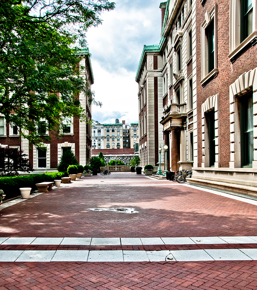 a brick plaza ensconced by a brick building and a garden