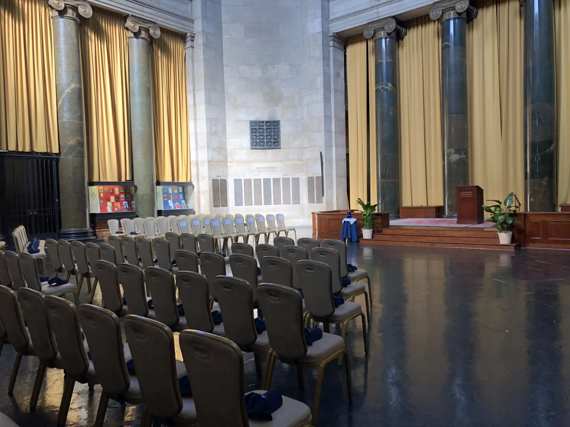 Rows of beige chairs face the wooden stage