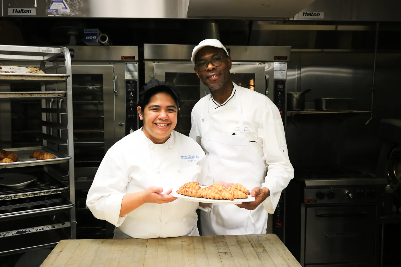Chef Leo and Rounds Cook Angela Acorita pose with a plate of fresh criossants they finished baking for Event Management's catering service