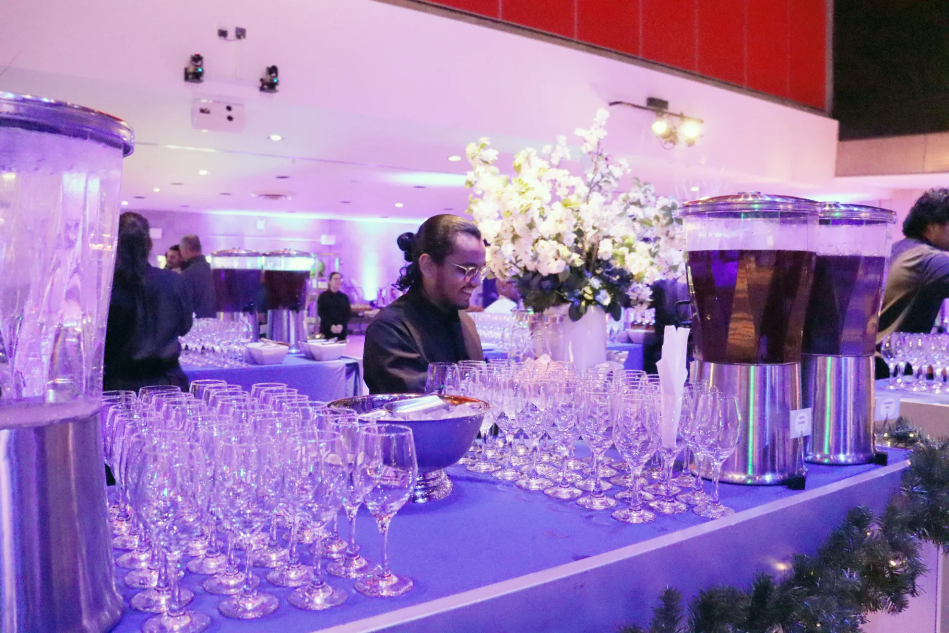 student worker creates mocktails for guests at a holiday party in lerner hall