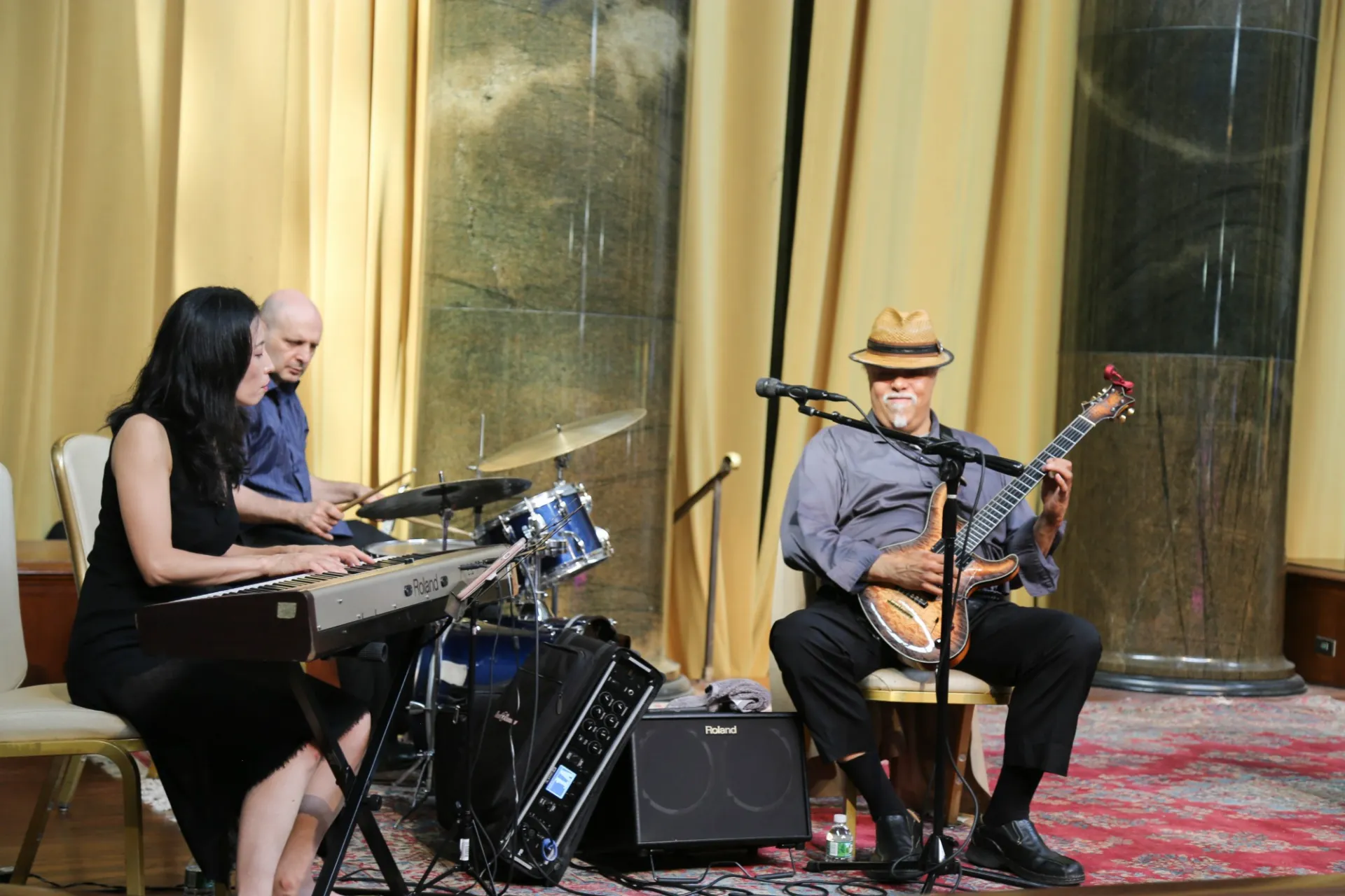 Small band plays on stage at an event in Low