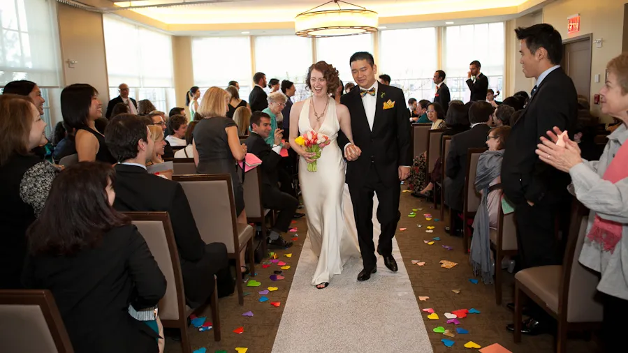 A bride and groom walk toward the camera down the aisle after saying their vows in a wedding ceremony at Faculty House